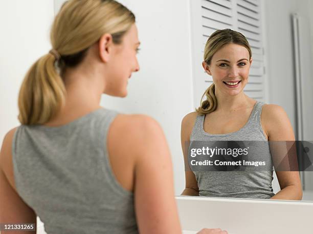 reflection of young woman in bathroom mirror - ponytail stock pictures, royalty-free photos & images