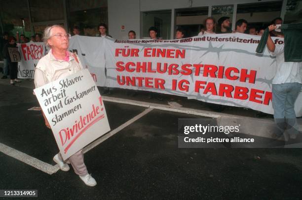 Ein Mann läuft am 21.8.1996 mit einem Plakat an anderen Demonstranten vorbei, die vor der Hauptversammlung der IG Farben in Abwicklung in einem...