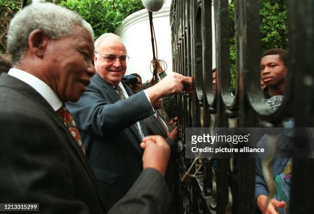 Durch den seinen Amtssitz in Kapstadt umgebenden Zaun schütteln der südafrikanische Präsident Nelson Mandela und sein Gast, Bundeskanzler Helmut...