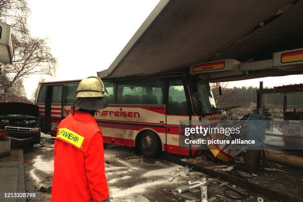 Ein Feuerwehrmann betrachtet einen Reisebus, der auf eisglatter Straße an der Autobahn-Rastanlage Garbsen bei Hannover in eine Tankstelle...