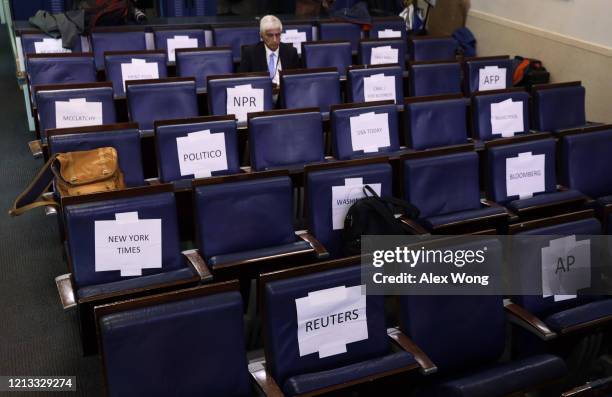 Journalist sits near signs that instruct social distancing prior to a news briefing at the James Brady Press Briefing Room of the White House March...