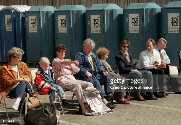 Vor einer Reihe provisorischer Toilettenhäuschen warten am 18.4.1996 Passagiere auf dem Vorfeld des Düsseldorfer Flughafens auf ihr Gepäck. Die...
