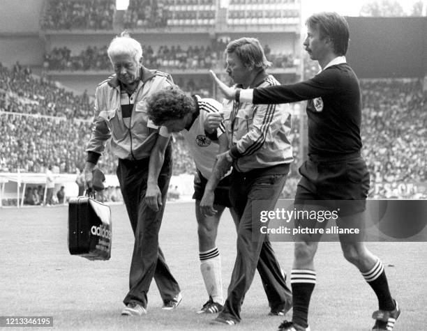 Der verletzte deutsche Mittelfeldspieler Paul Breitner wird von Masseur Erich Deuser und Mannschaftsarzt Prof. Heinrich Heß gestützt. Der Schweizer...