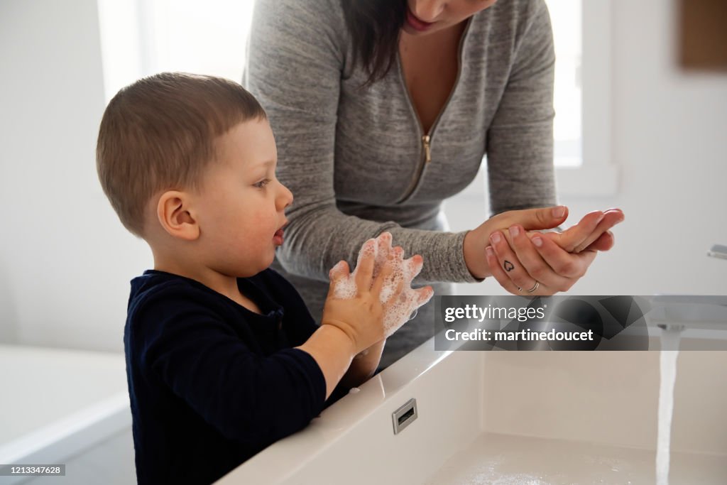 Mother teaching young son how to wash his hands in quarantine isolation Covid-19