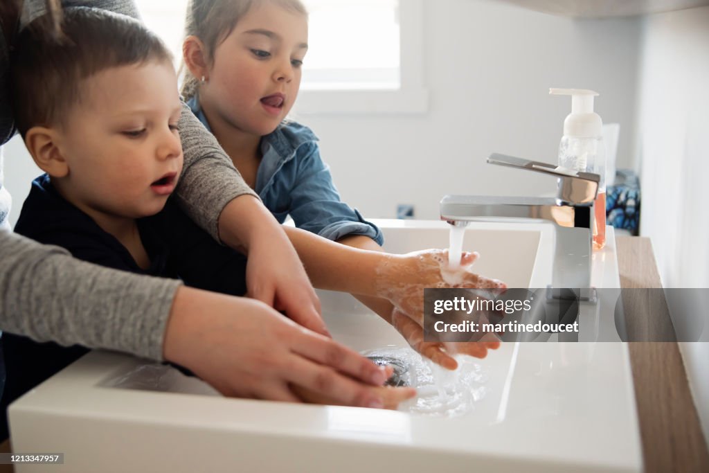 Mother teaching young children how to wash their hands in quarantine isolation Covid-19