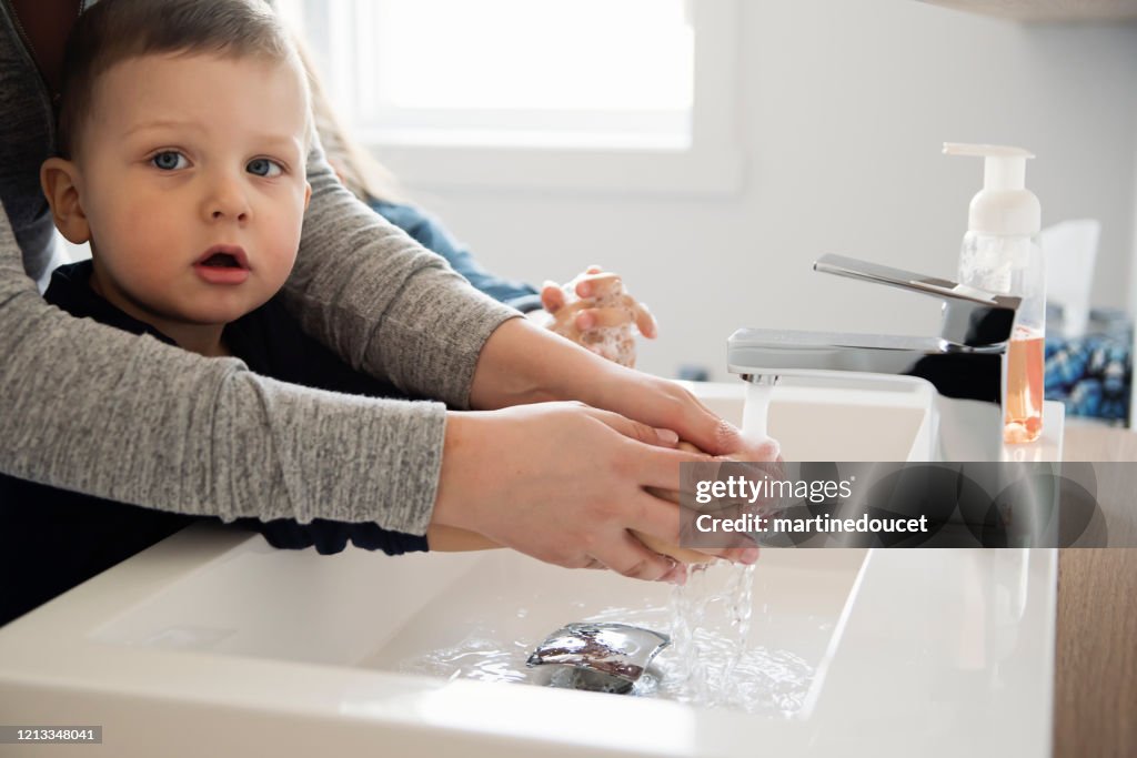 Mãe ensinando crianças pequenas como lavar as mãos em isolamento de quarentena Covid-19
