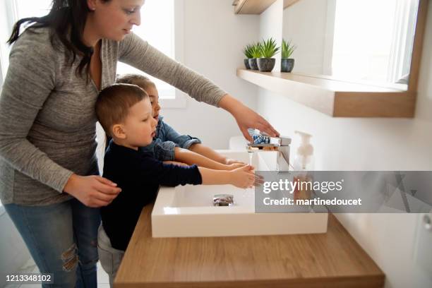 mutter lehrt kleine kinder, wie man ihre hände in quarantäne-isolation zu waschen covid-19 - washing hands stock-fotos und bilder
