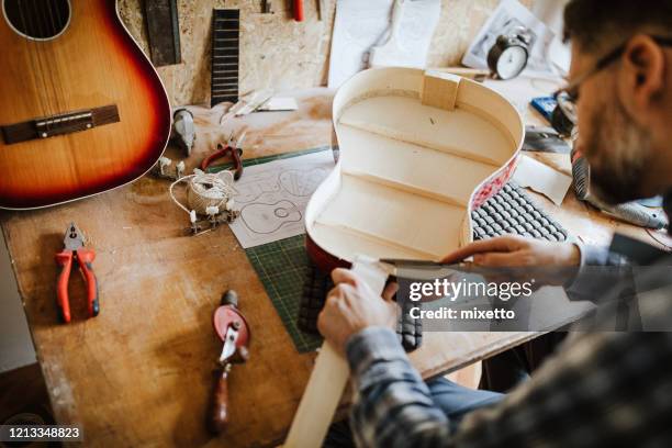 man repairing acoustic guitar at his workshop - make music day stock pictures, royalty-free photos & images