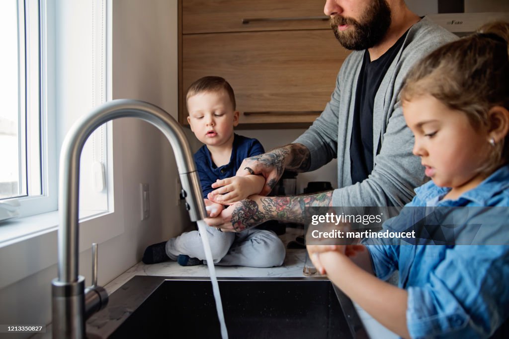 Vater lehrt kleine Kinder, wie man ihre Hände in Quarantäne-Isolation zu waschen Covid-19
