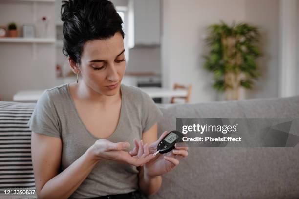 vrouwen die de niveaus van de bloedsuiker door glucosemeter controleren - glucose stockfoto's en -beelden