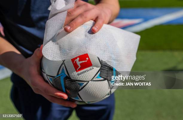 The ball is disinfected after the German first division Bundesliga football match RB Leipzig v SC Freiburg on May 16, 2020 in Leipzig, eastern...