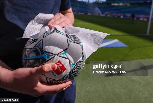 The ball is disinfected after the German first division Bundesliga football match RB Leipzig v SC Freiburg on May 16, 2020 in Leipzig, eastern...