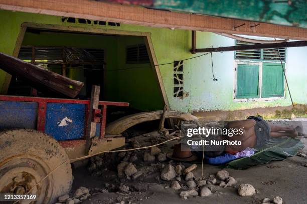 Resident sleeps on a banana leaf near his house that has been buried by mud due to a flash flood in Poi Village, South Dolo Subdistrict, Sigi...