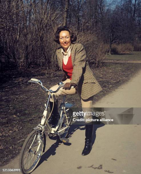 Die deutsche Schriftstellerin Utta Danella im Reitdress auf einem Fahrrad auf dem Weg zu ihrem Pferd. Aufnahme von 1975.