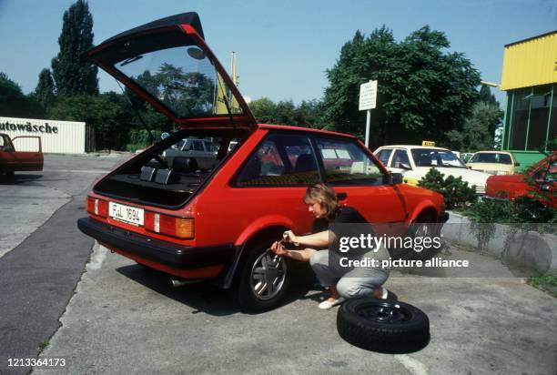 Eine junge Frau entfernt vor dem Reifenwechsel die Radkappe, aufgenommen 1987.