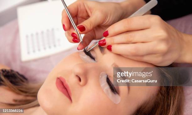 kosmetikerin füllt lash line mit individuellen falschen wimpern mit pinzette - stockfoto - false eyelash stock-fotos und bilder