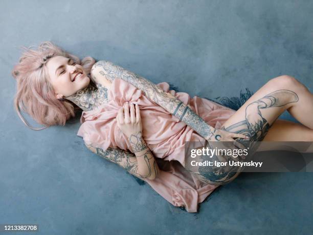 young tattooed woman with pink hair lying on floor - nose piercing stock pictures, royalty-free photos & images