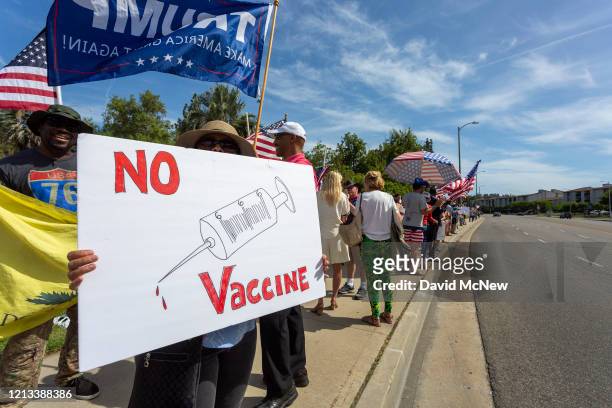 Protester holds an anti-vaccination sign as supporters of President Donald Trump rally to reopen California as the coronavirus pandemic continues to...