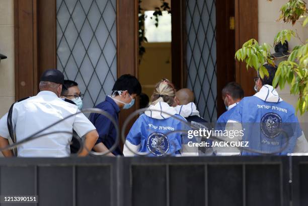 Israeli police officers and forensics experts talk to people at the gated house of the Chinese ambassador where he was found dead, in Herzliya on the...
