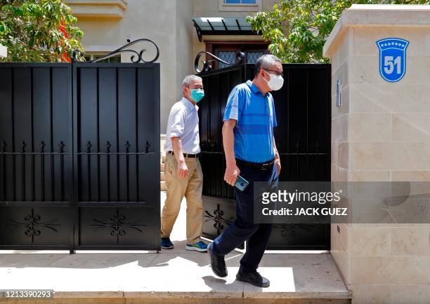 Unidentified men walk out of the residence of Israel's Chinese ambassador on the outskirts of Tel Aviv after he was found dead on May 17, 2020. - The...