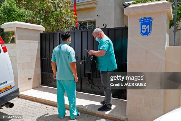 Physicians stand at the entrance of the residence of Israel's Chinese ambassador on the outskirts of Tel Aviv after he was found dead on May 17,...