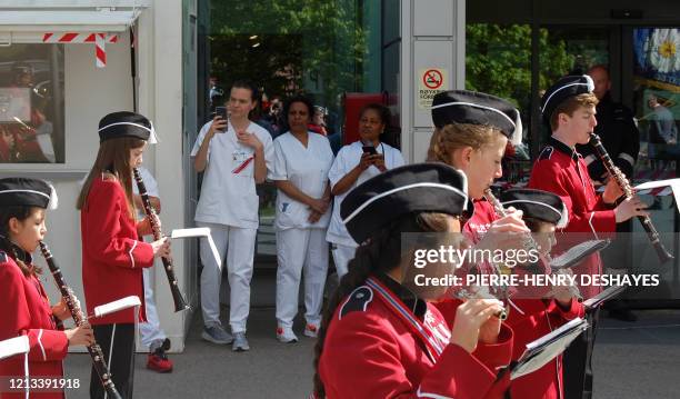 Medical staff members look on as a school marching band plays in front of a hospital in Baerum, near Oslo, for the Norwegian Constitution day...