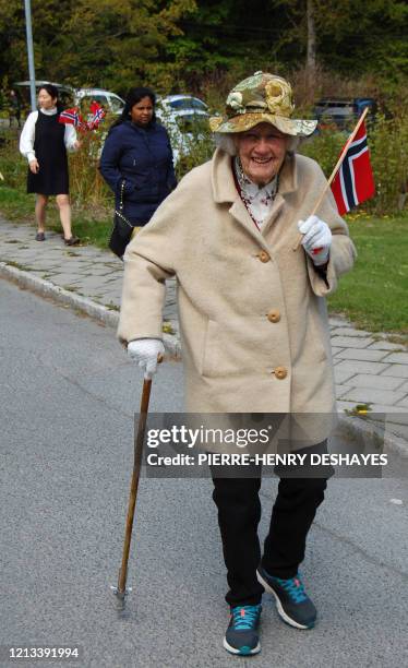 An old lady carries a Norwegian flag as she follows a school marching band playing in Baerum, near Oslo, during the Norwegian Constitution day...