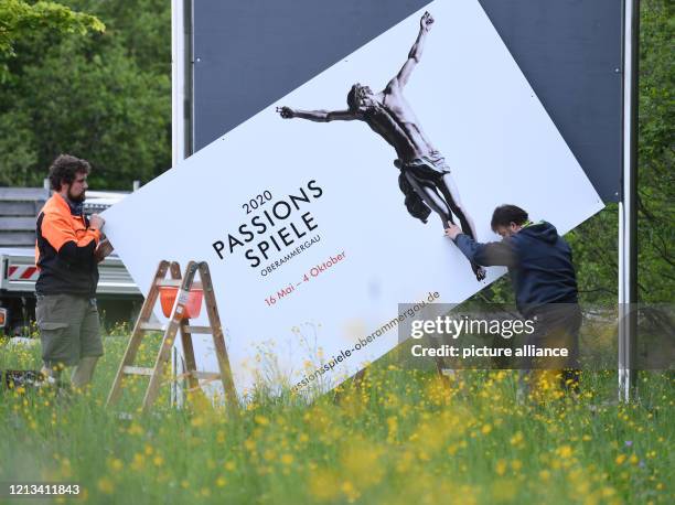 May 2020, Bavaria, Oberammergau: Employees of the Bauhof remove one of the advertising posters of the Passion Play 2020. The Oberammergau Passion...