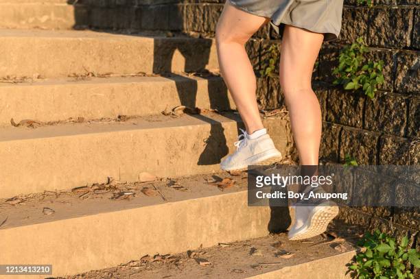 cropped view of fitness runner woman training herself by running up steps on staircase in urban street. - female muscle calves stock pictures, royalty-free photos & images