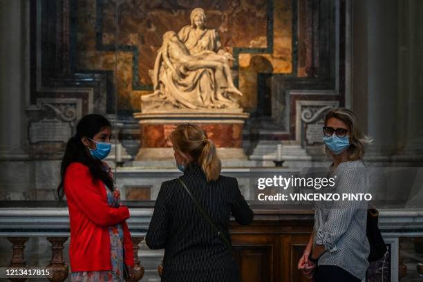 People stand by Michelangelo's Pieta while visiting St. Peter's Basilica as it reopens on May 18, 2020 in The Vatican during the lockdown aimed at...