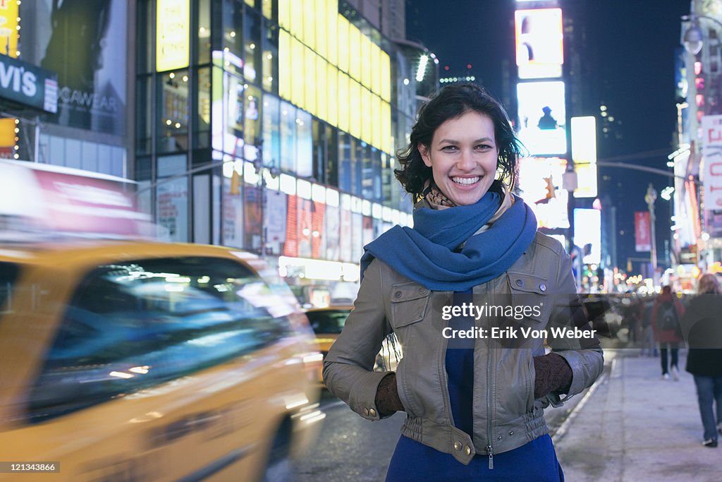 Cab passing woman in Times Square at night