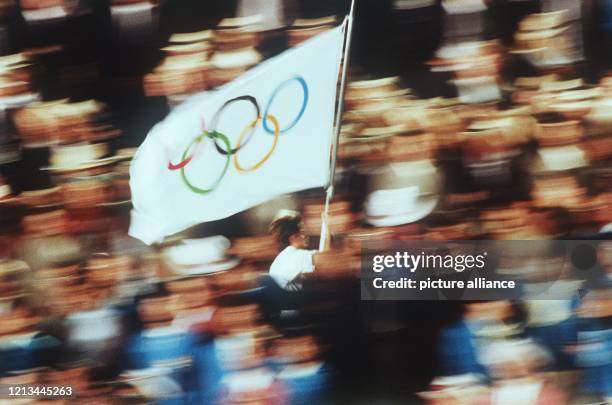 Die von einer Läuferin getragene Olympiafahne mit den fünf Olympischen Ringen "flattert" beim feierlichen Eröffnungszeremoniell der Olympischen...