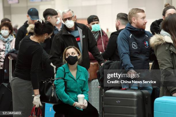 Passengers wearing face masks wait to check in at waiting hall of Toronto Pearson International Airport on March 18, 2020 in Toronto, Canada.