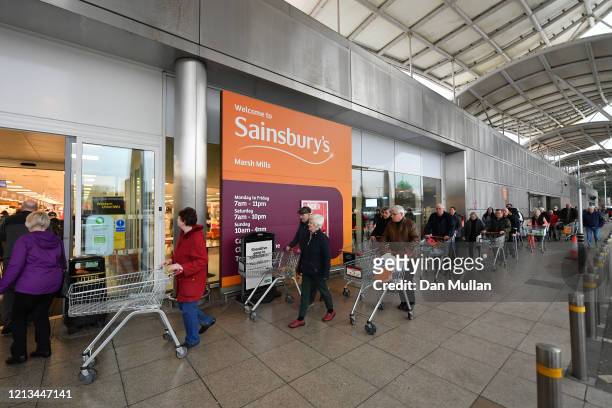 Shoppers queue outside a Sainsbury's supermarket prior to opening in Plymouth on March 19, 2020 in Plymouth, United Kingdom. The store allowed only...