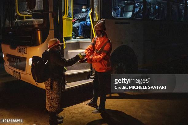 Mine employee sanitises the hands of a mine worker, en route to his evening shift at the Sibanye-Stillwater platinum mine, before boarding a company...