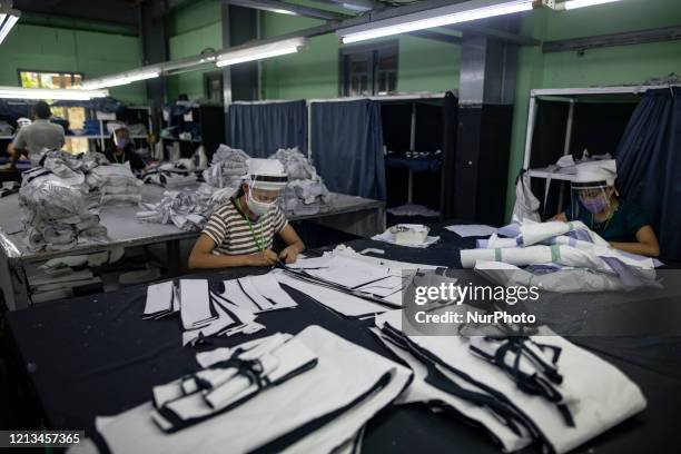 Workers wearing face masks and face shields as part of preventative measures against the COVID-19 novel coronavirus, as they working at a garment...