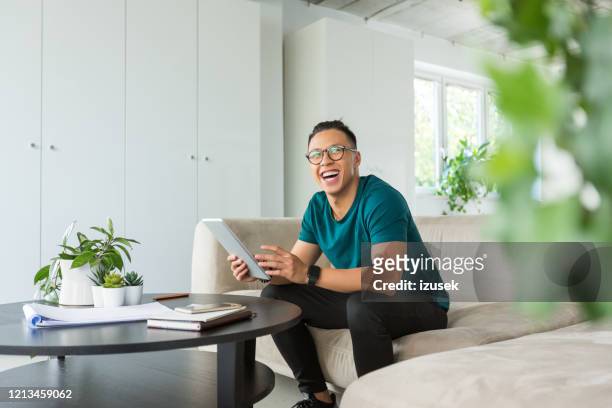 giovane sorridente che lavora su tablet digitale in ufficio - casual chic foto e immagini stock