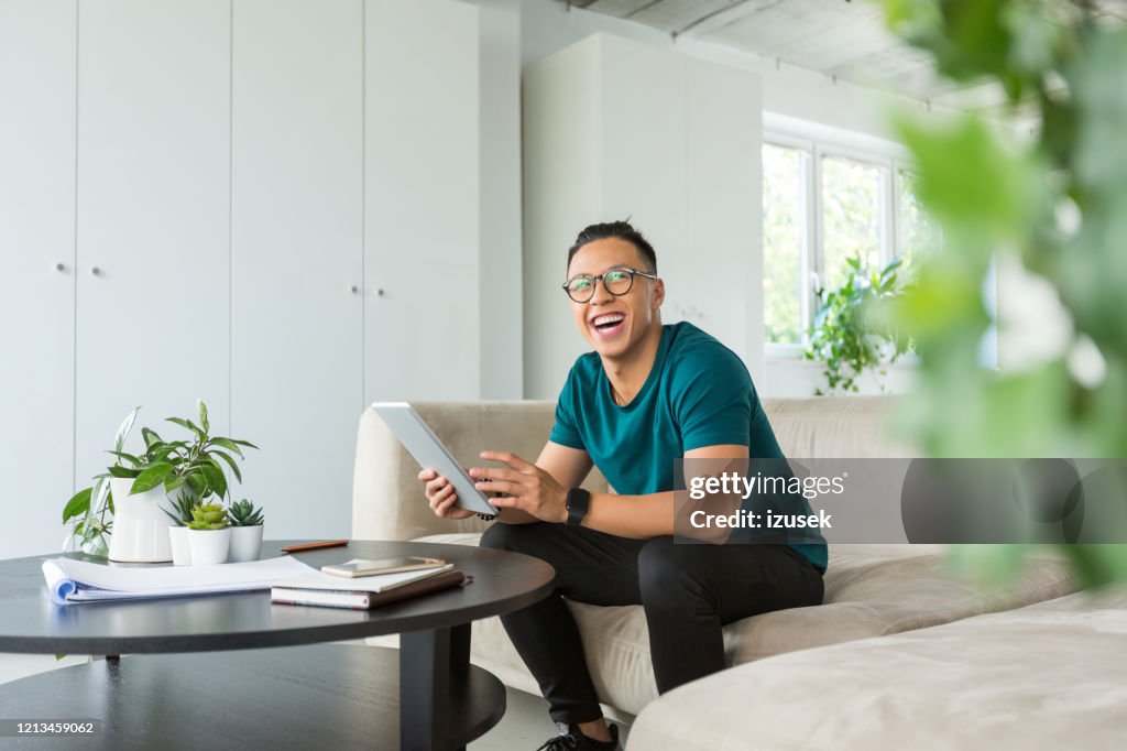 Smiling young man working on digital tablet in the office