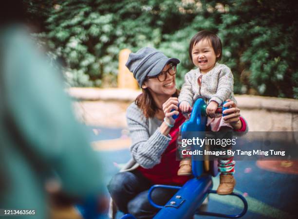 mom & daughters playing seesaw joyfully in playground - seesaw - fotografias e filmes do acervo