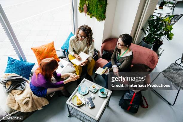 aerial view of three colleagues having meeting in cafe - small business lunch stock pictures, royalty-free photos & images