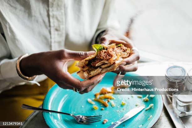 woman eating tasty vegan burger - vegetarian stock-fotos und bilder