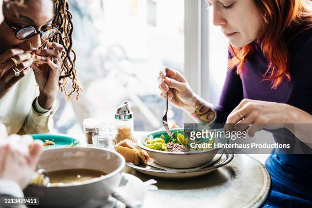 woman enjoying vegan meal with friends - geniessen teller essen stock-fotos und bilder