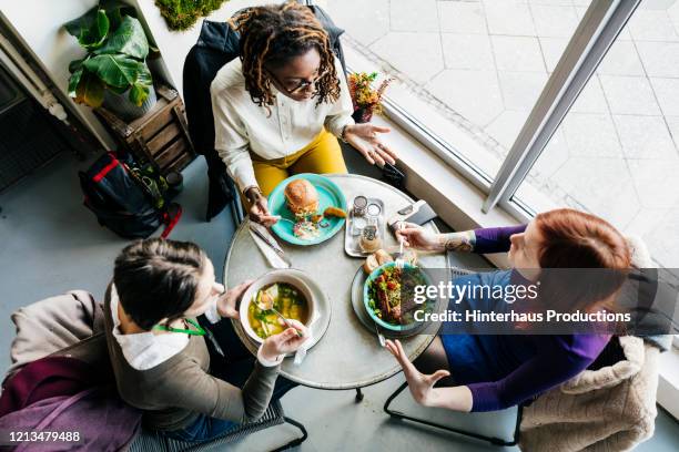 aerial view of three women eating in vegan cafe - round table stock pictures, royalty-free photos & images