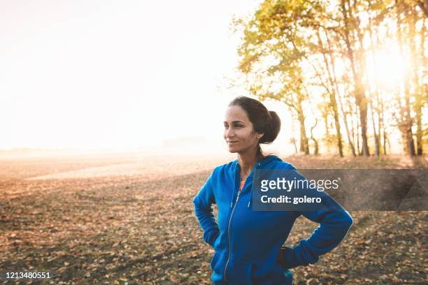 sportswoman standing on field at sunrise - mid adult stock pictures, royalty-free photos & images