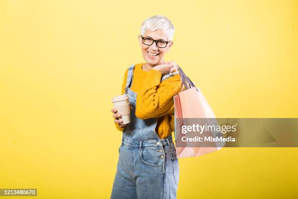 cheerful woman holding a cup of coffee - shopping coloured background stock pictures, royalty-free photos & images