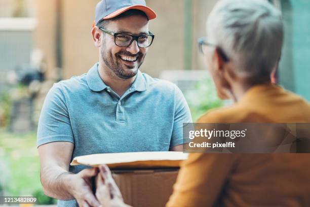 delivery man handing boxes and packages to the recipient - carrying boxes stock pictures, royalty-free photos & images