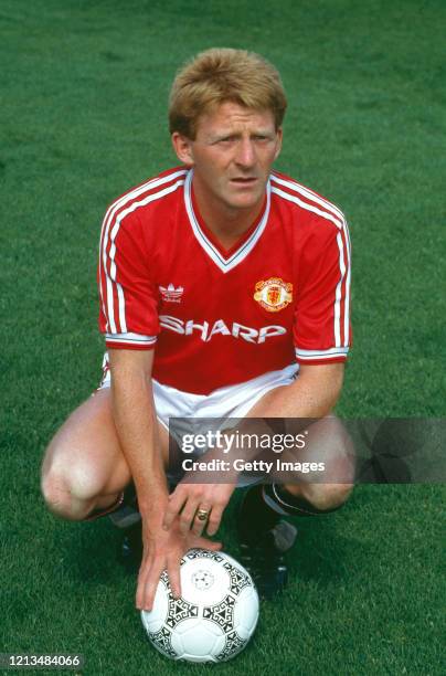 Manchester United player Gordon Strachan pictured kneeling with an Adidas match ball during the Squad photo call ahead of the 1987/88 season,...