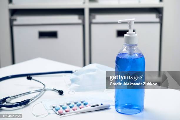 respiratory disposable medical mask, thermometer, antibacterial and hand sanitizer, stethoscope, tablets and medications on a blue background. - hand sanitiser stock pictures, royalty-free photos & images