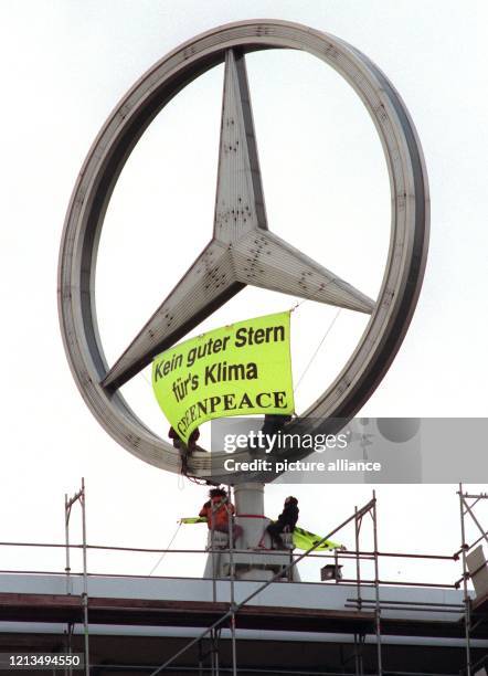 Mitglieder der Umwelt-Organisation Greenpeace befestigen am am Mercedes-Stern des Verwaltungsgebäudes in Stuttgart-Untertürkheim ein Transparent mit...