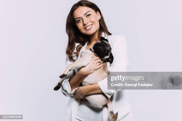 a laughing and smiling auburn haired woman in a white dress, is staring most lovingly at her cute pug, who calmly sits on the hands, gaining her undivided attention. isolated white background. - dog white background stock pictures, royalty-free photos & images